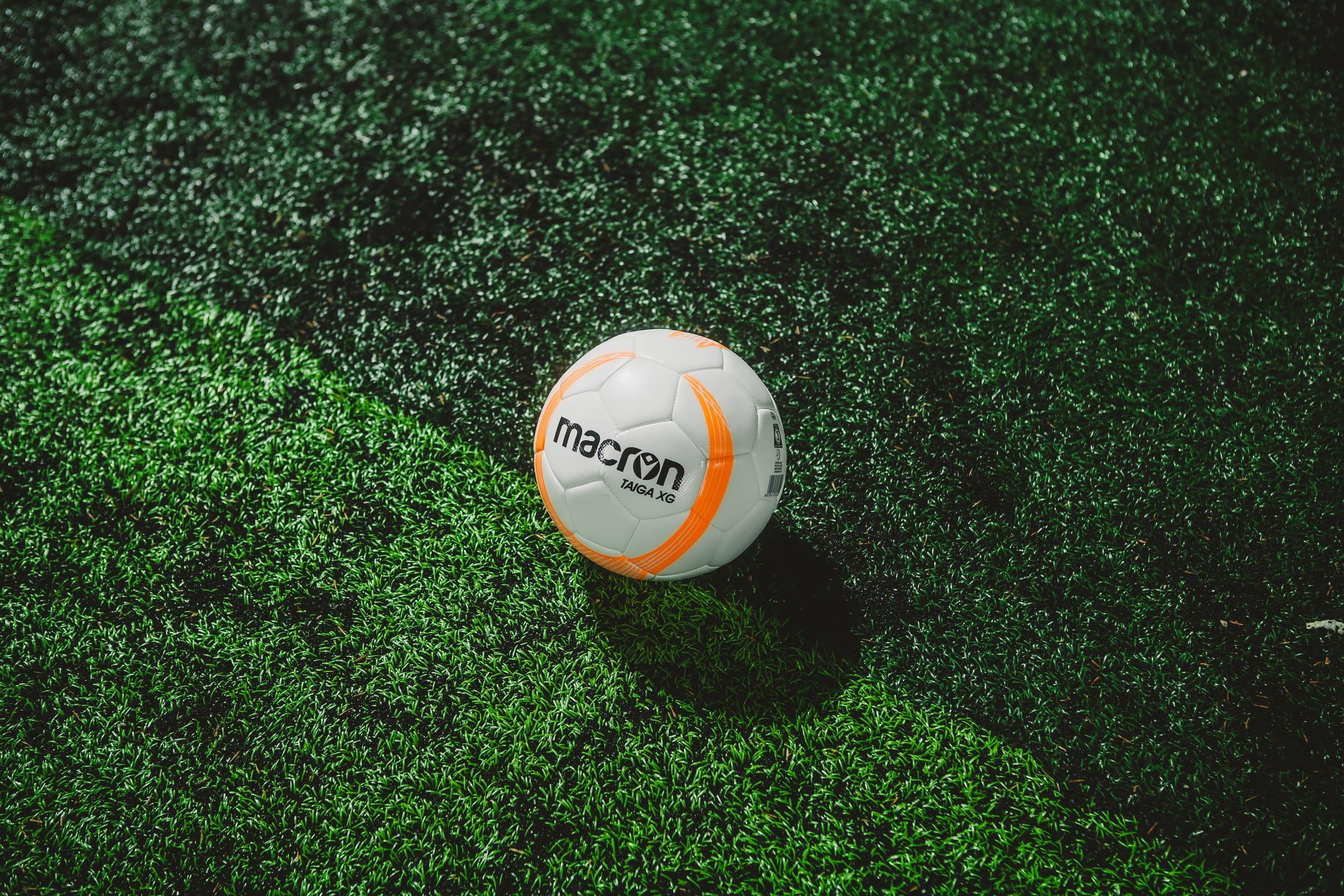 Pelota de fútbol quieta sobre el césped sintético oscuro del galpón
